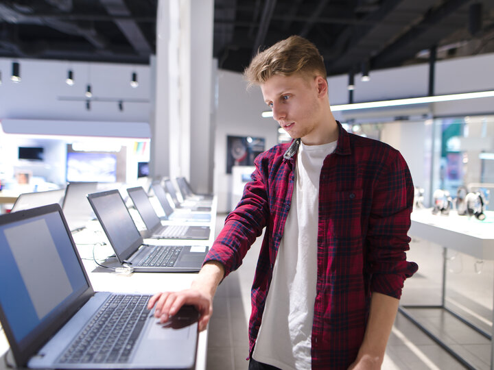 A man buys a laptop in a technology store